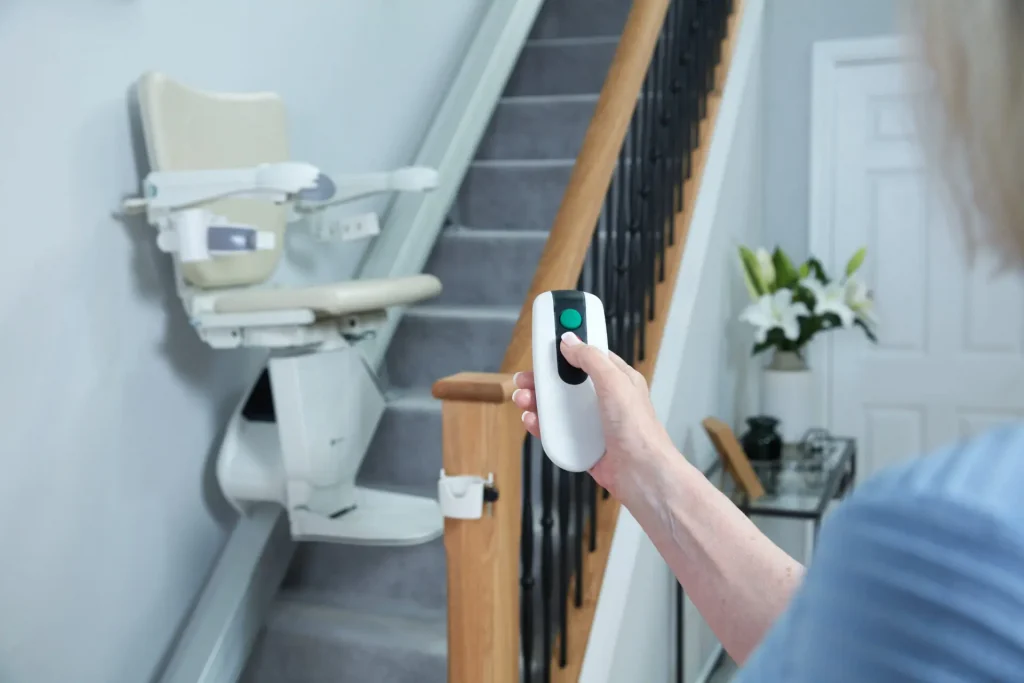 A woman uses her remote control to call her handicare 1100 stairlift.