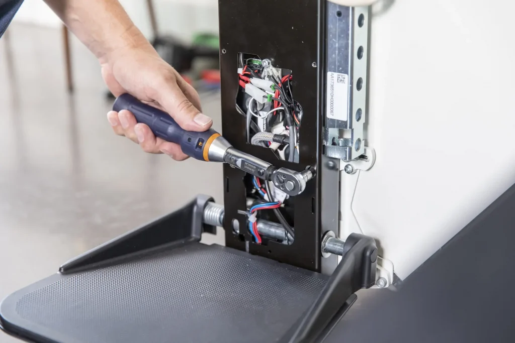 A man uses a socket set to fit a plate onto a newly-repaired stairlift.