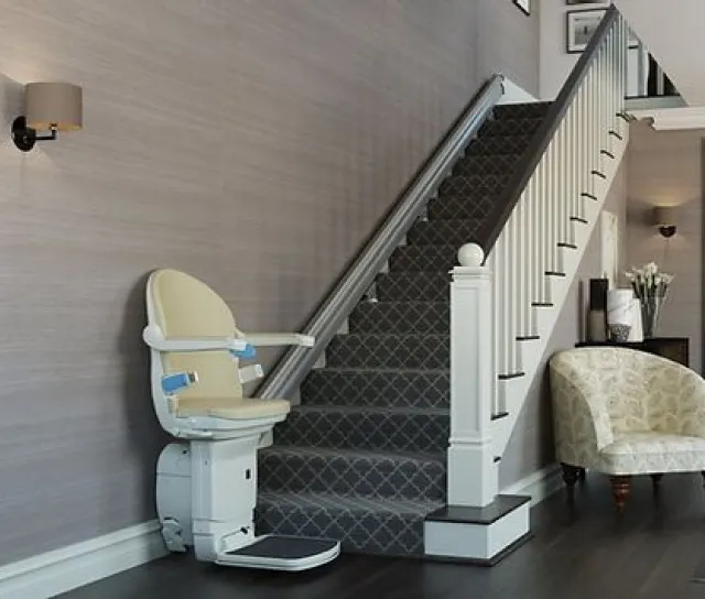 A stairlift waits at the bottom of a flight of stairs.