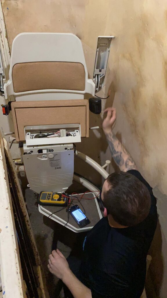 An Engineer servicing a stairlift at a customers home.