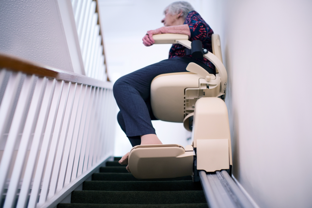 Senior woman sitting on stair lift at home