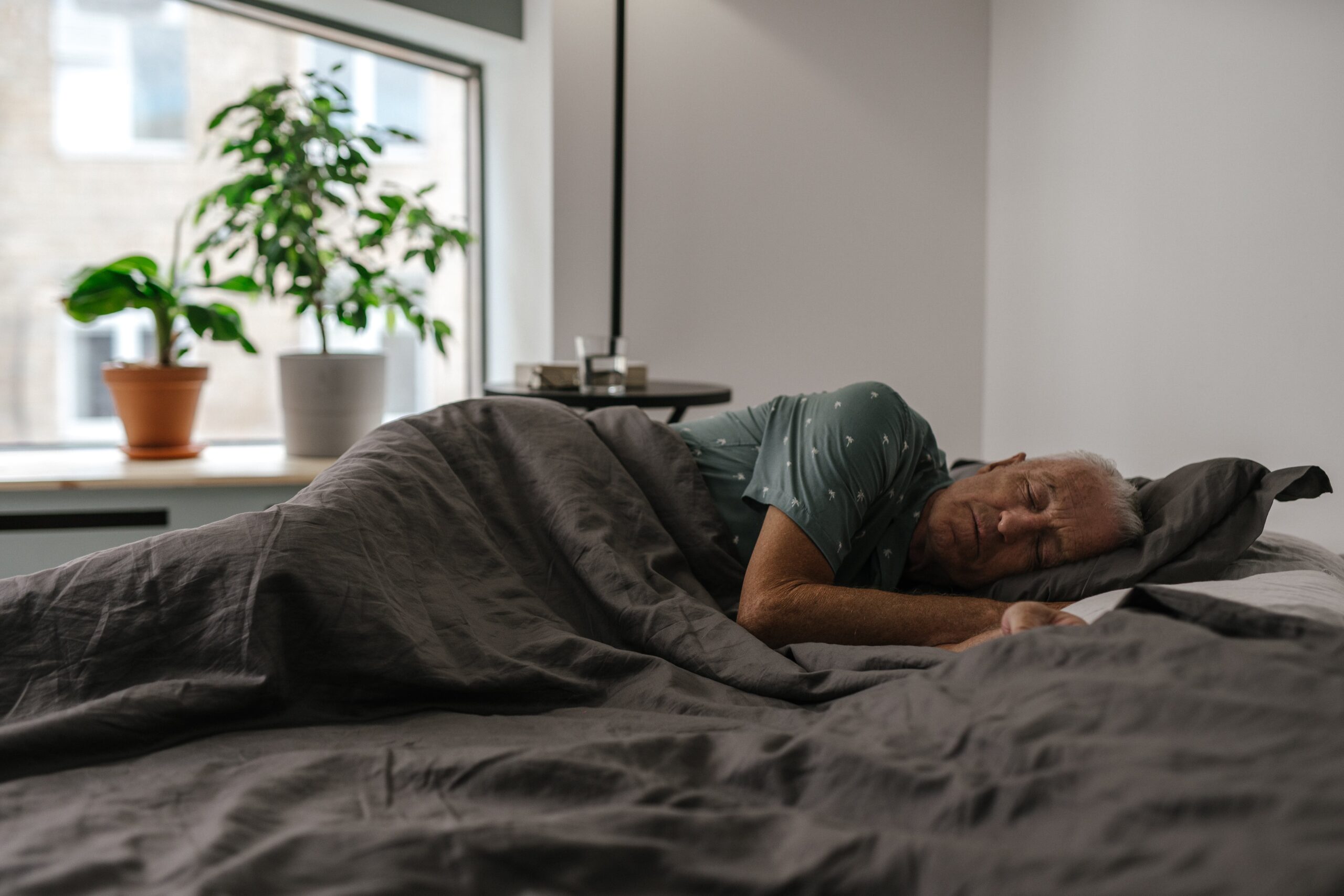 an elderly man improving sleep quality by resting in a bed in his house.