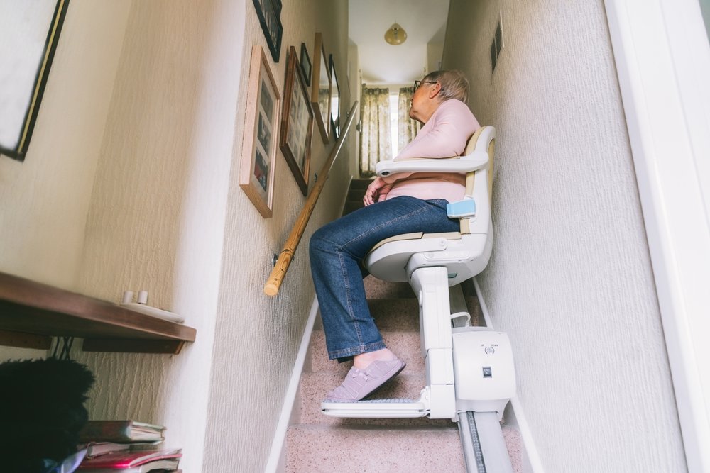 Senior Woman Using Automatic Stair Lift On A Staircase