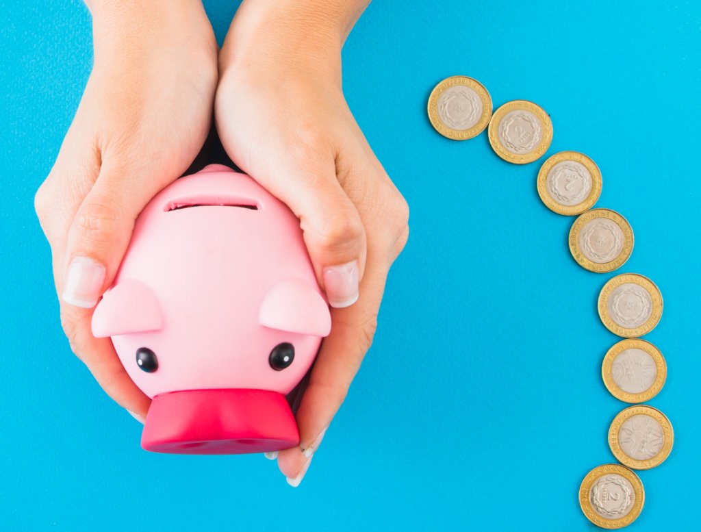 A woman holding a piggy bank with money saved next to her.