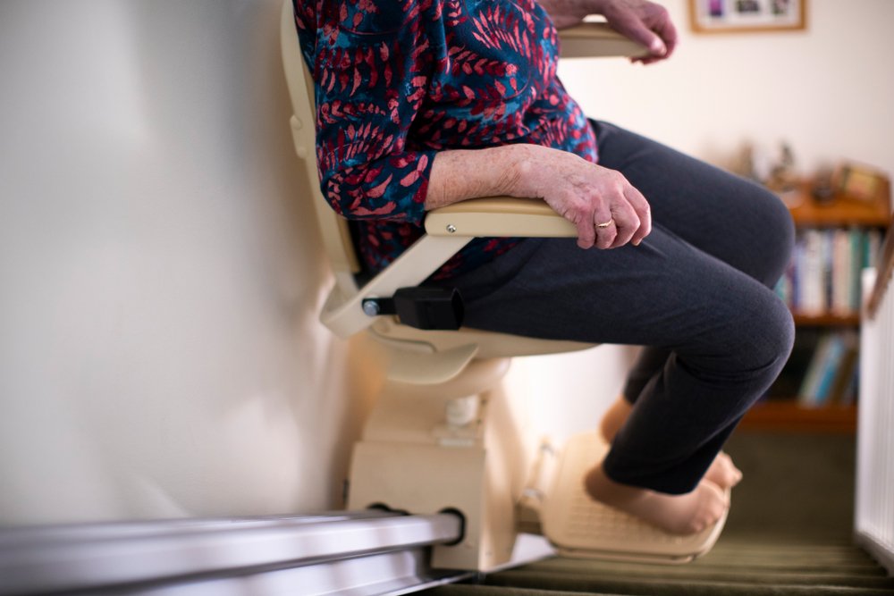 Senior,Woman,Sitting,On,Stair,Lift,At,Home