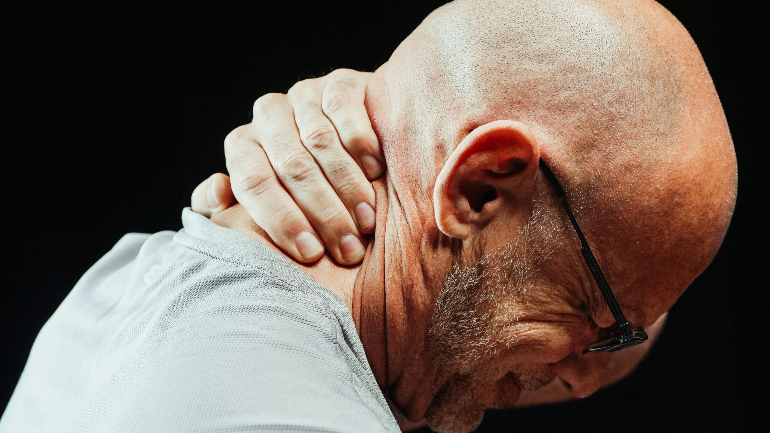 an elderly man experiencing neck pain